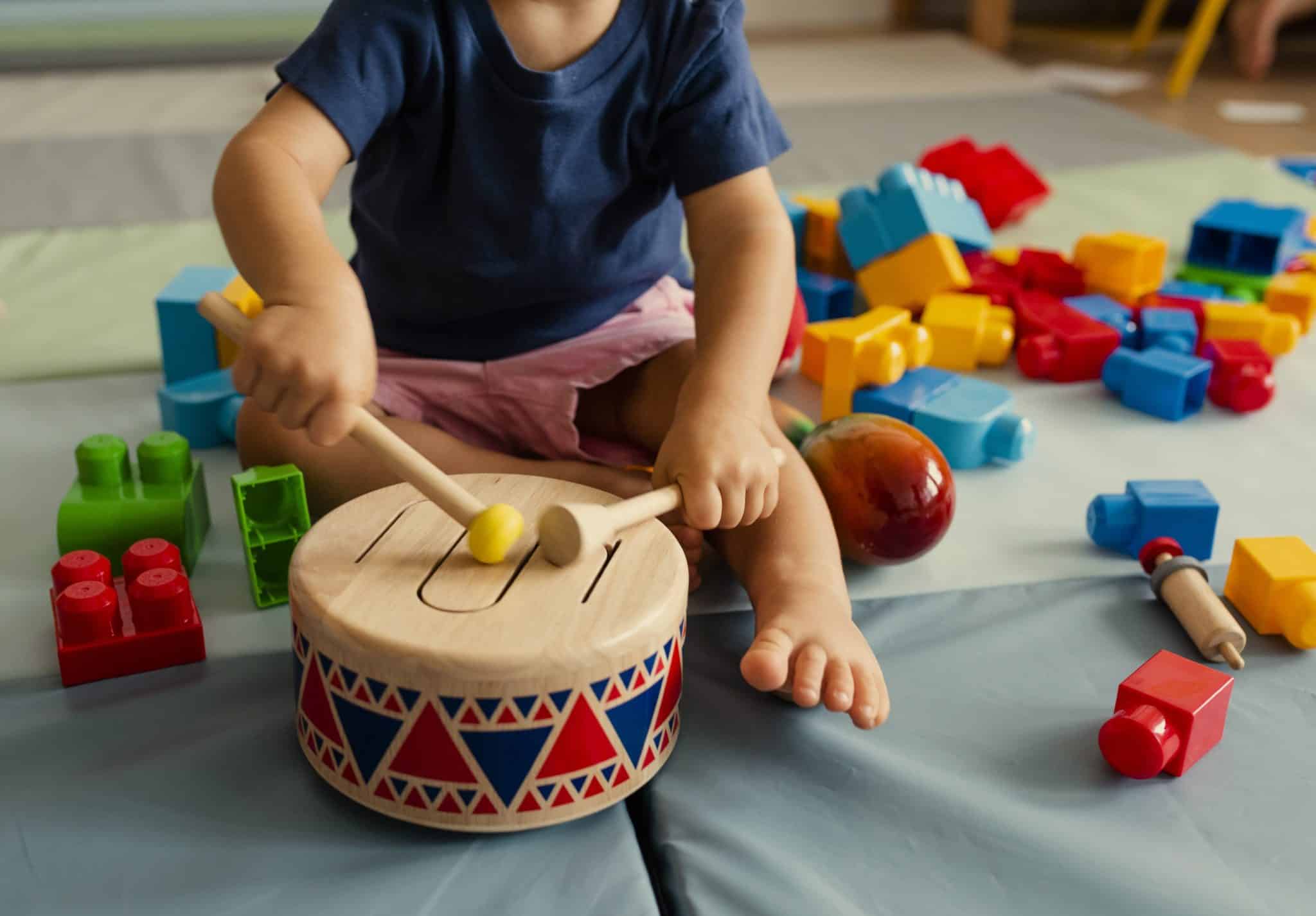 small child playing with a toy drum