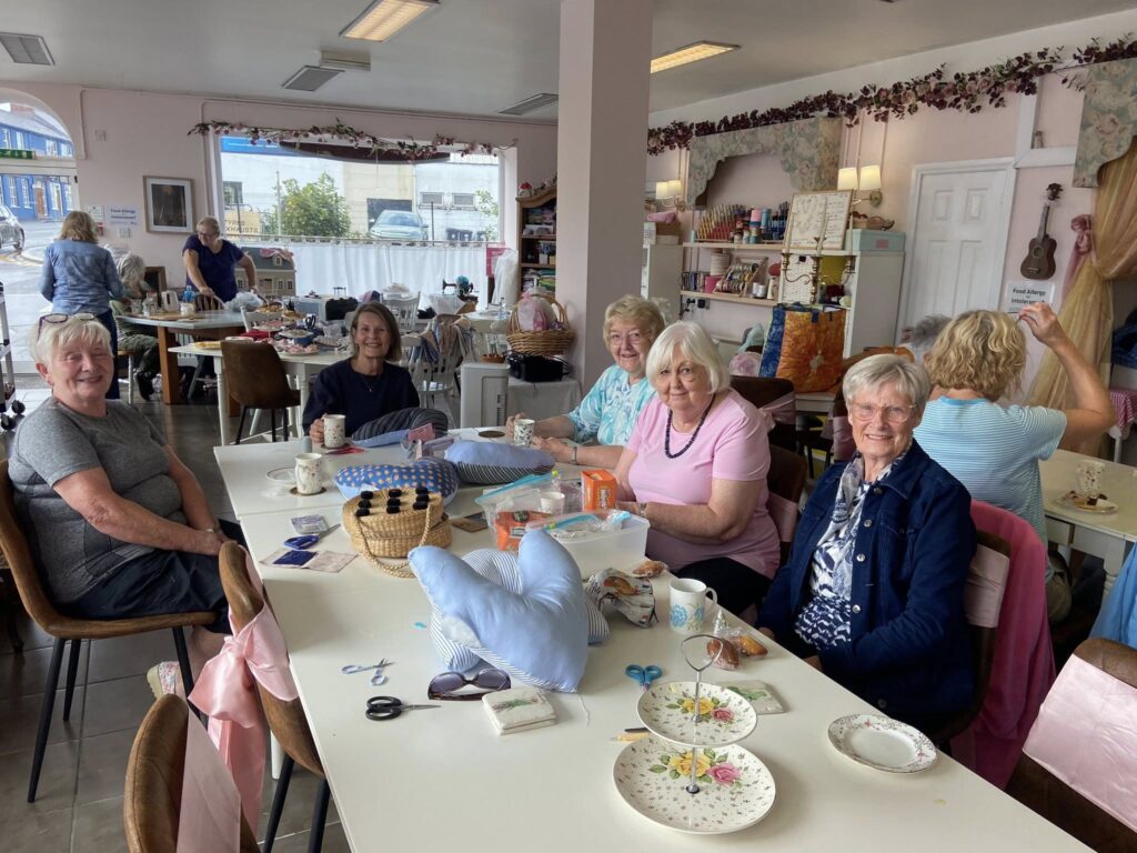 group of women sitting around a table knitting